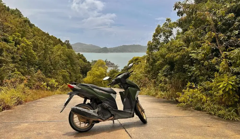 A scooter parked on a hillside road on Koh Phangan, looking out over the sea